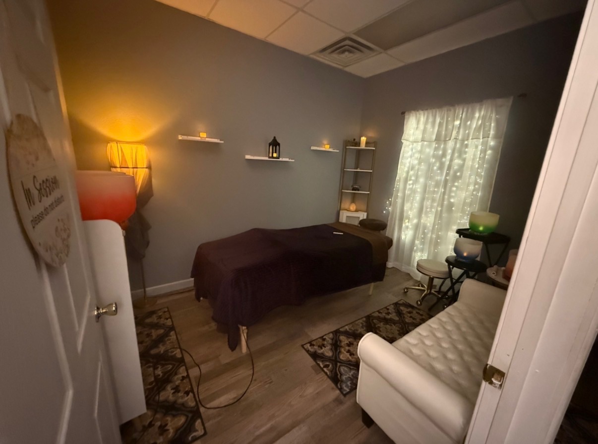 Our massage room with a dressed table, warm corner lamp, wall candles and a fairy-light curtain