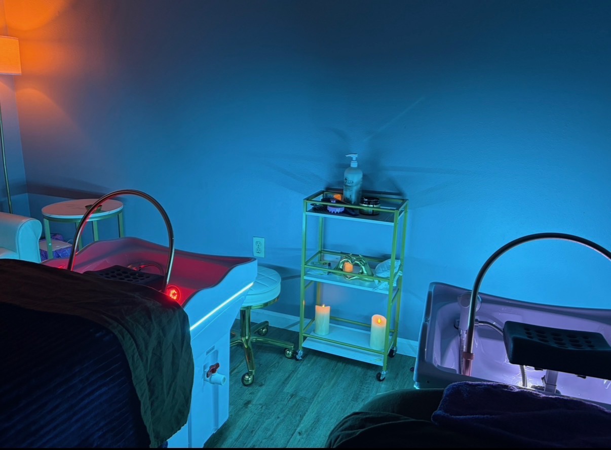 Our treatment room under blue LED light with the red light therapy bed, gold cart, candles and head spa basin